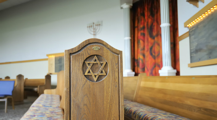 View of a synagogue sanctuary with the focal point being a wooden pew with a Star of David carved on its side