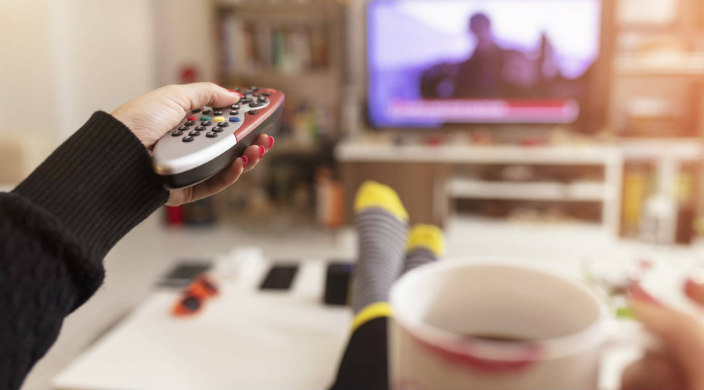 Hand using a remote to change the tv channel from within a cozy home atmosphere