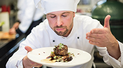 A chef enjoys the pleasing odor of a well-cooked meal.