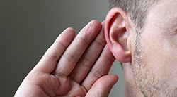 a man cups his ear to listen