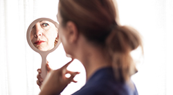 woman looks in mirror to reflect on her embodying Jewish values