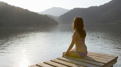 A person meditates in a quiet spot near a lake