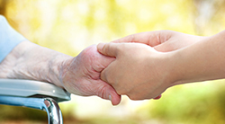 Social worker holds the hand of a senior person