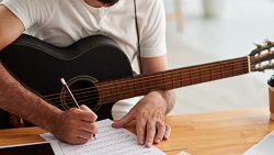 a person with a guitar writes music