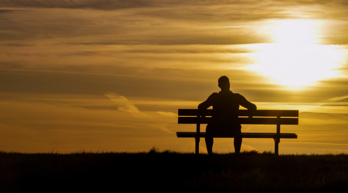 Person sitting on a bench (in shadow) watching the sky