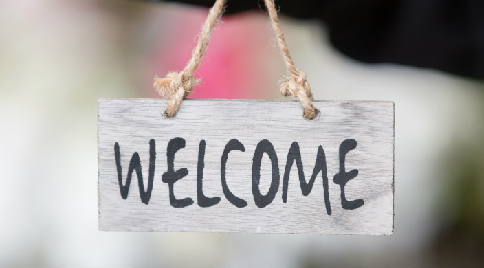 Wooden welome sign hanging from a rope string