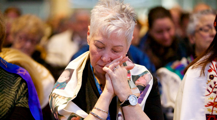 Woman praying with her eyes closed, hands held near her face