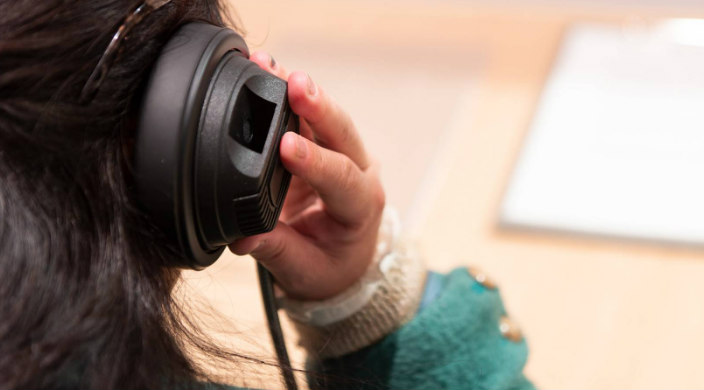 Back of a womans head wearing large headphones